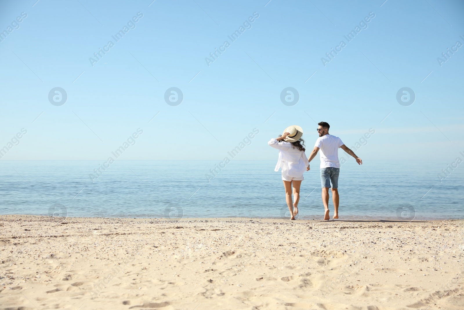 Photo of Young couple running on beach near sea. Honeymoon trip