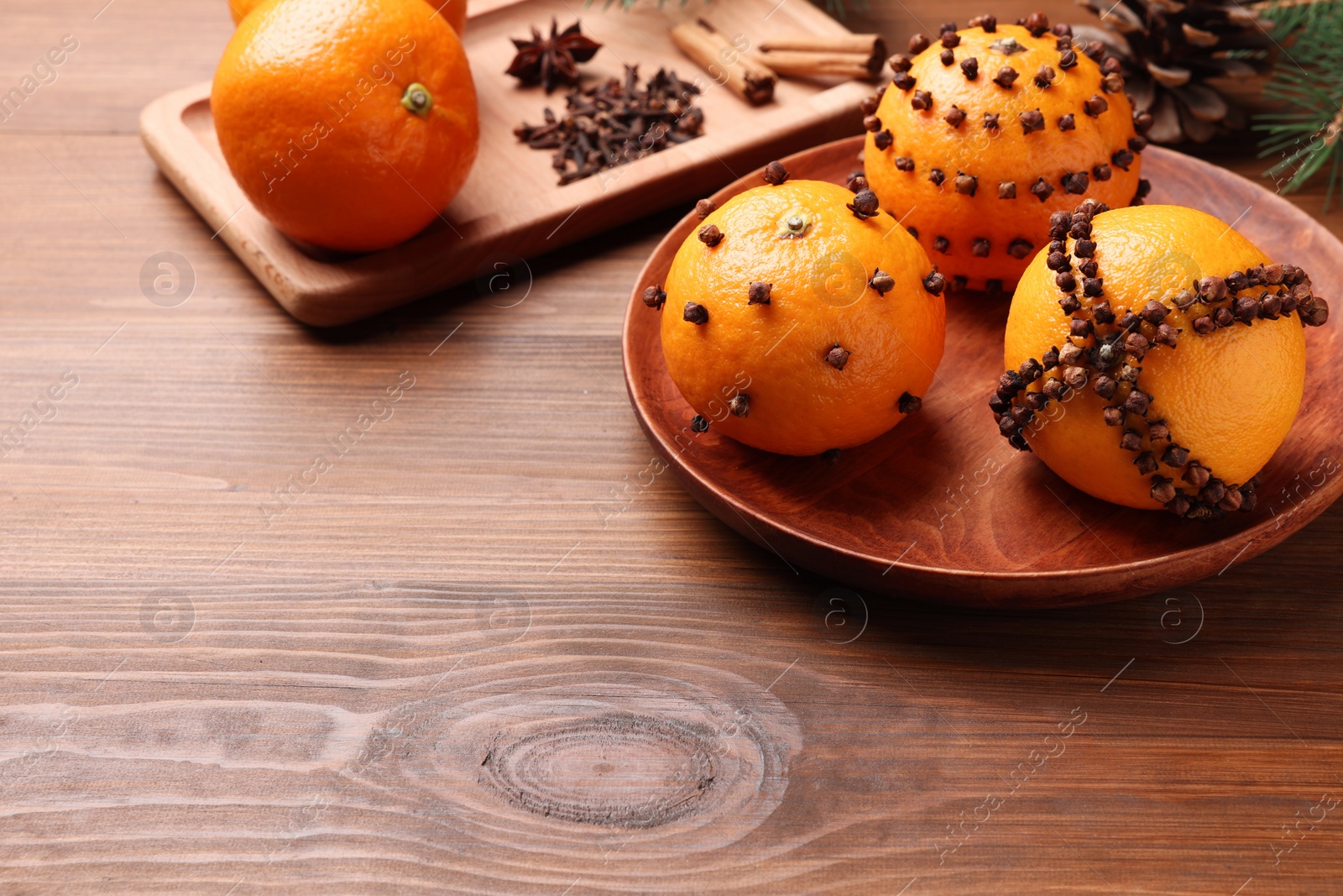 Photo of Pomander balls made of tangerines with cloves on wooden table. Space for text