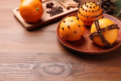 Photo of Pomander balls made of tangerines with cloves on wooden table. Space for text