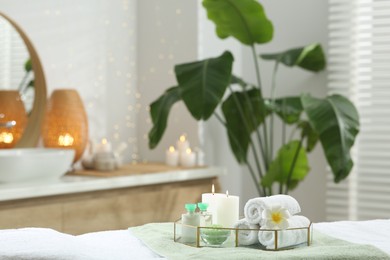 Composition with different spa products and burning candles on table indoors. Space for text