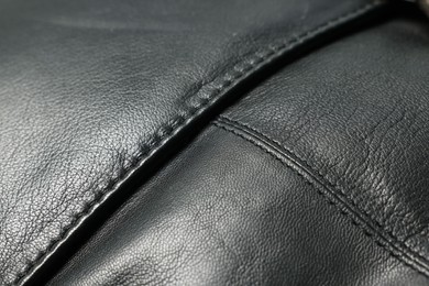 Black natural leather with seams as background, closeup