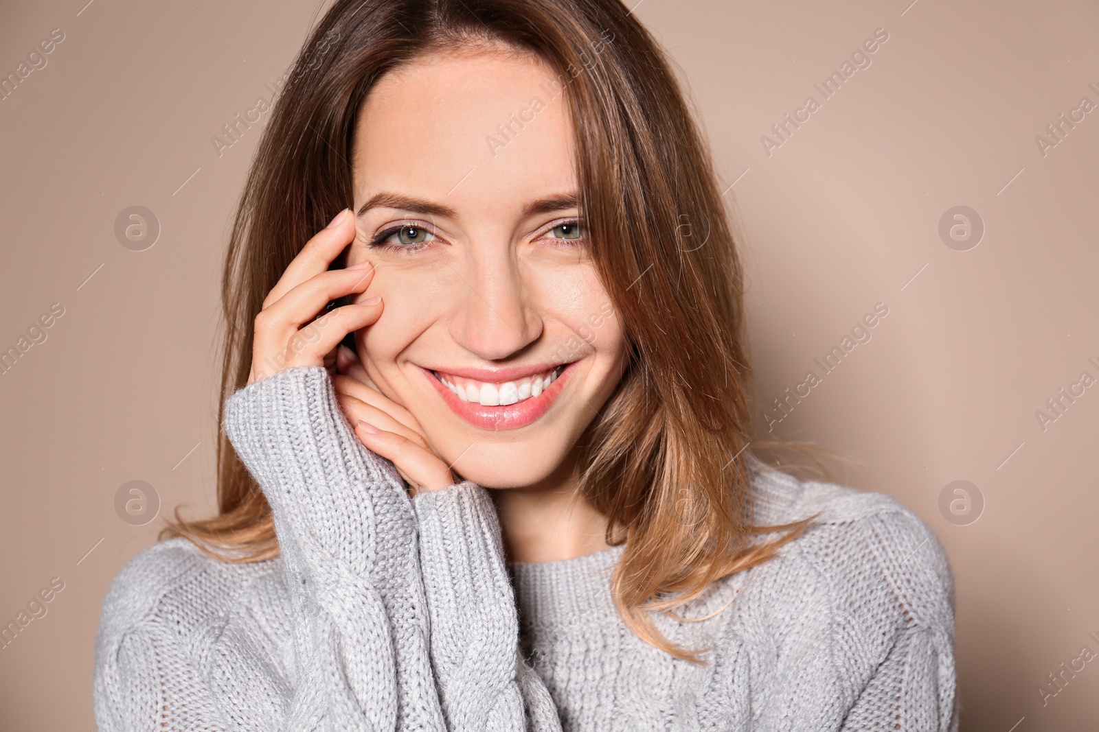 Image of Happy young woman wearing warm sweater on beige background 