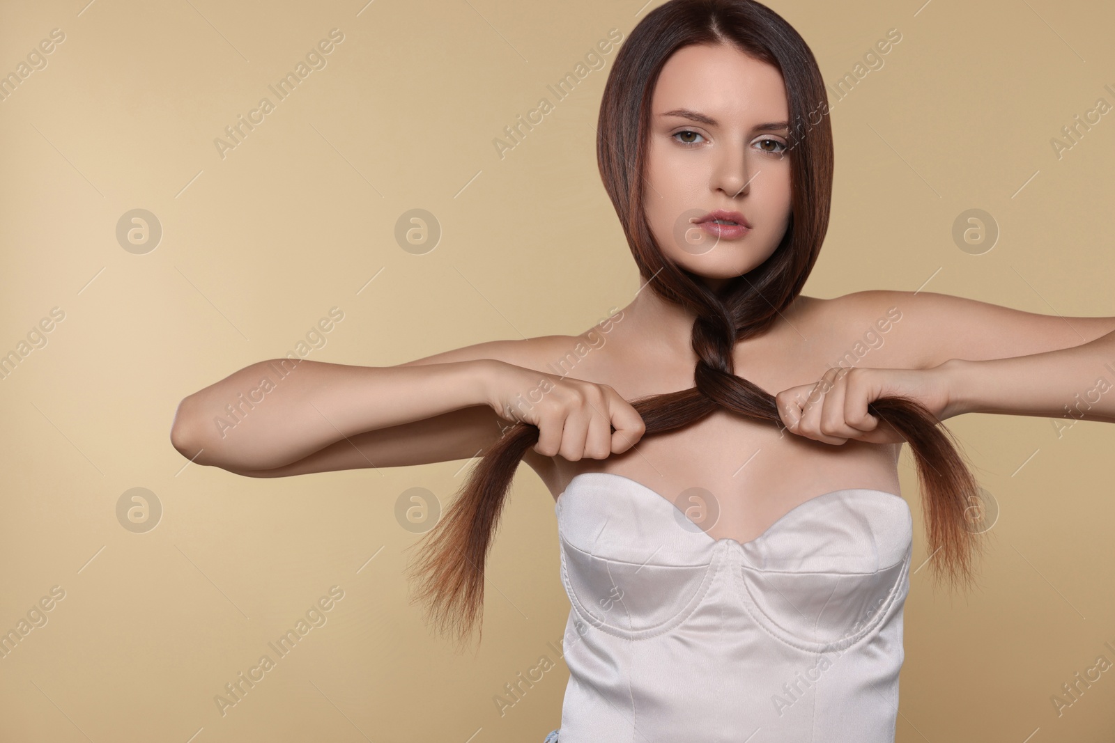 Photo of Portrait of beautiful young woman with healthy strong hair on beige background