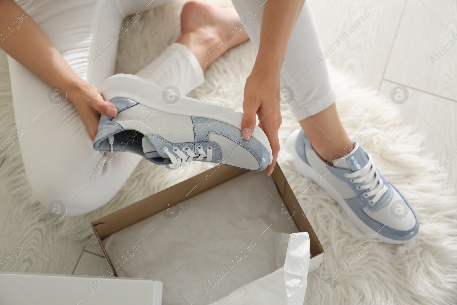 Photo of Woman measuring new stylish sneakers indoors, closeup