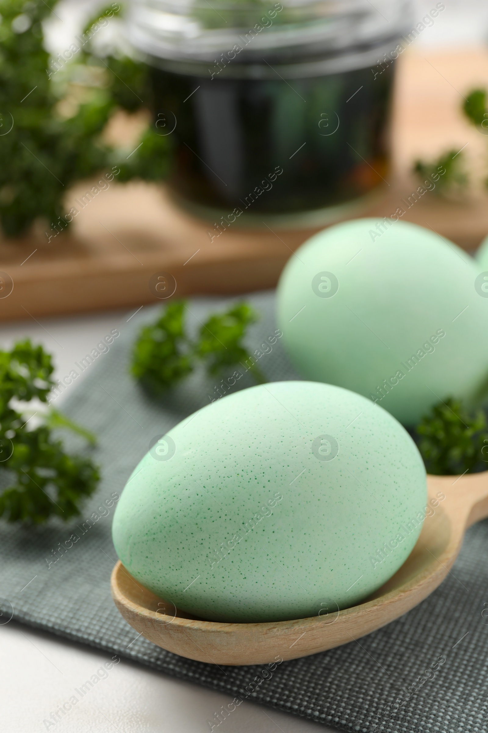 Photo of Turquoise Easter eggs painted with natural dye and curly parsley on table, closeup