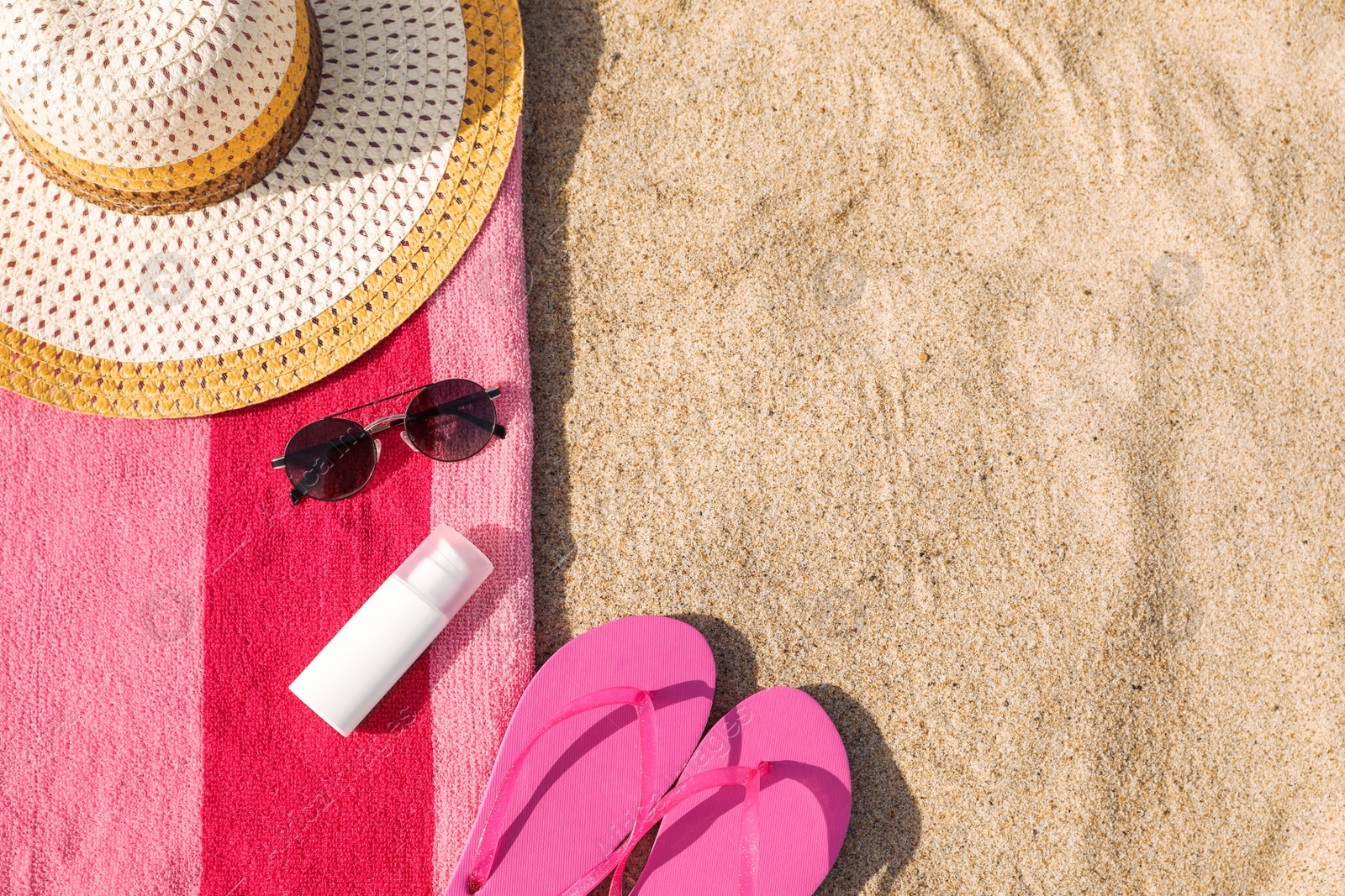 Photo of Towel and beach accessories on sand, flat lay. Space for text