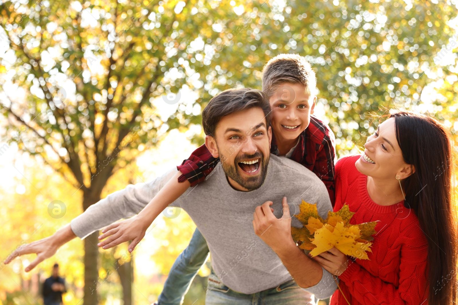 Photo of Happy family with son spending time in park. Autumn walk