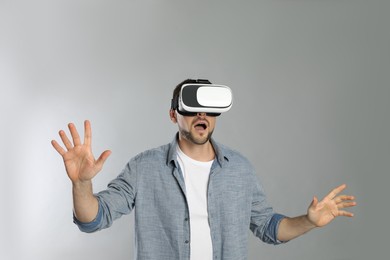 Photo of Man using virtual reality headset on grey background