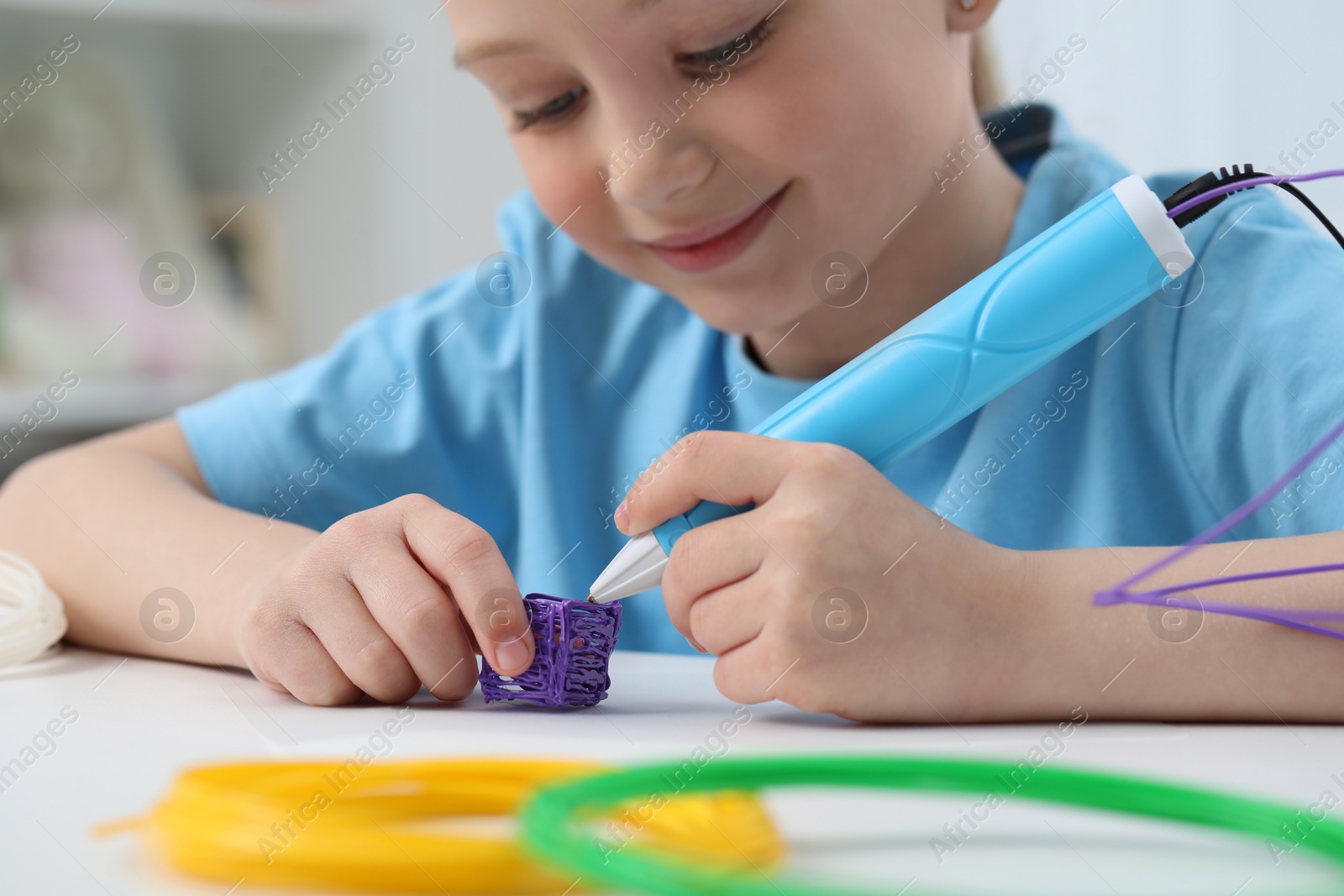 Photo of Girl drawing with stylish 3D pen at white table indoors, selective focus