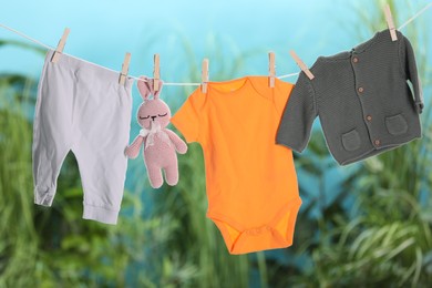 Baby clothes and bunny toy drying on laundry line outdoors