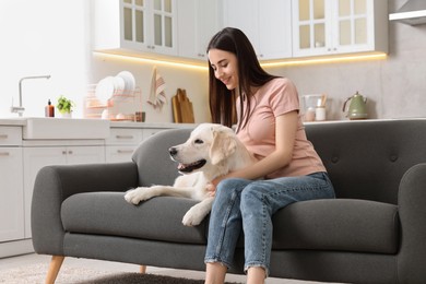 Photo of Happy woman with cute Labrador Retriever dog on sofa at home. Adorable pet