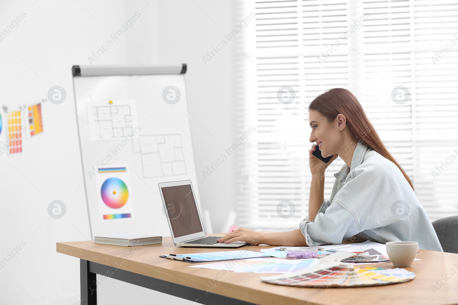 Photo of Interior designer talking on mobile phone in office