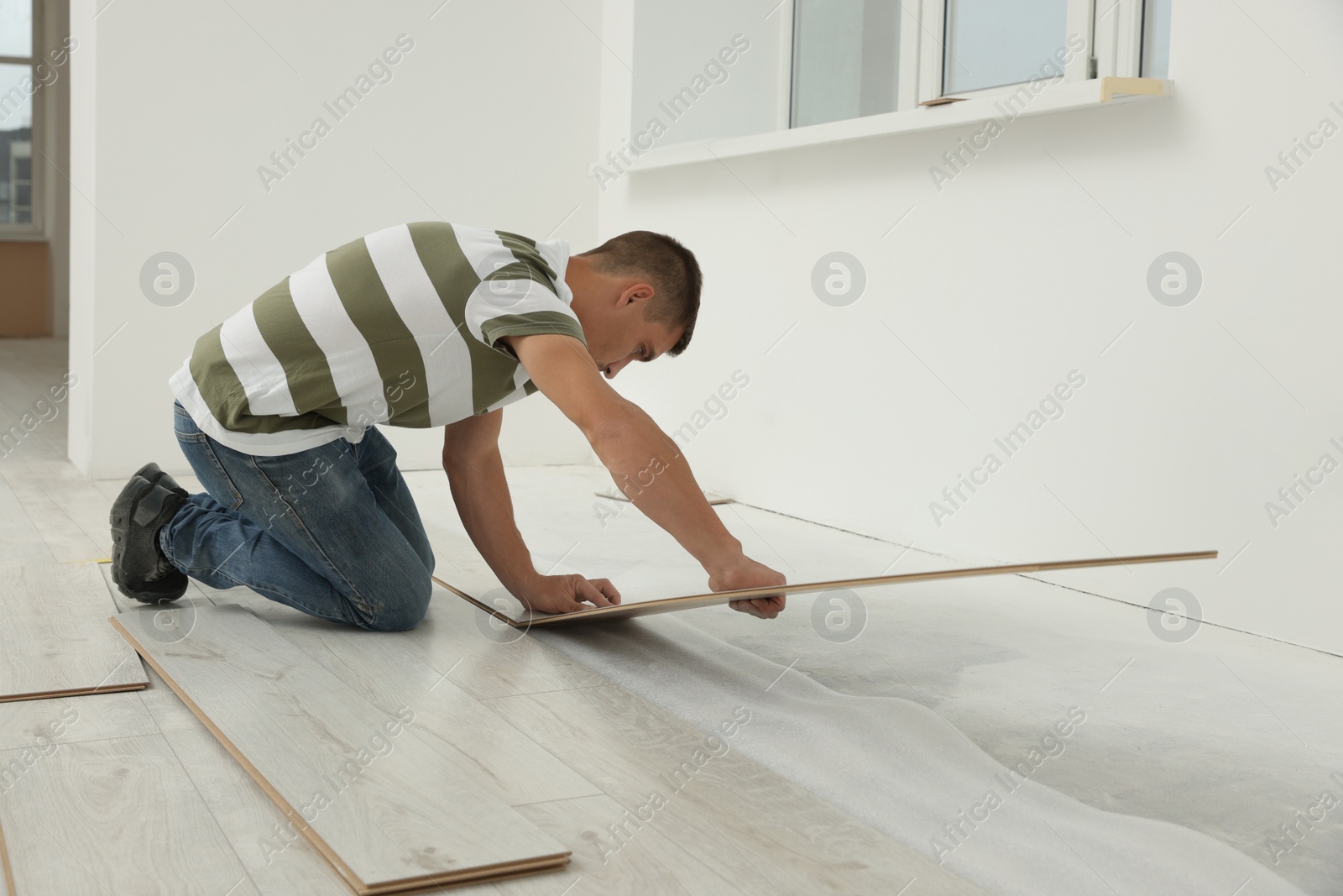 Photo of Professional worker installing new laminate flooring indoors