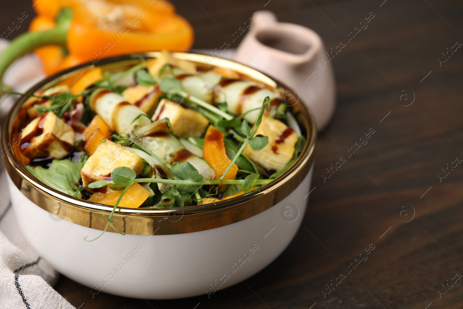 Photo of Delicious salad with tofu, vegetables and balsamic vinegar on wooden table, closeup. Space for text