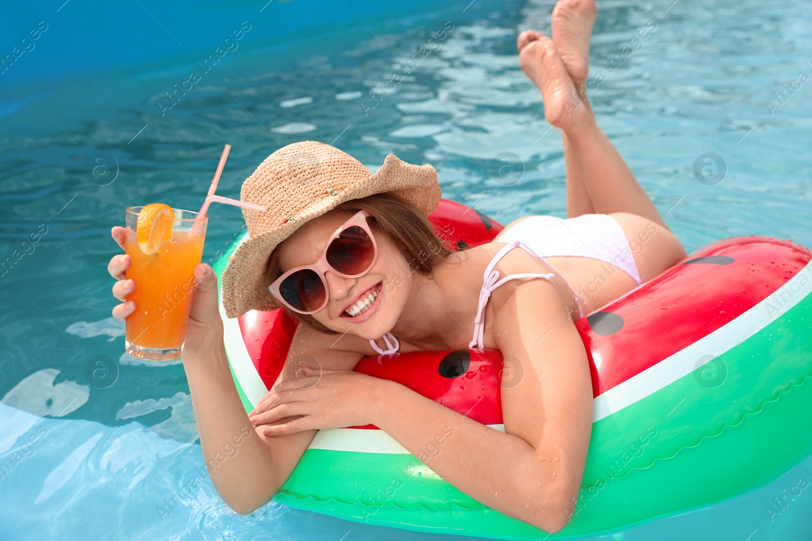 Photo of Young woman with cocktail in pool on sunny day