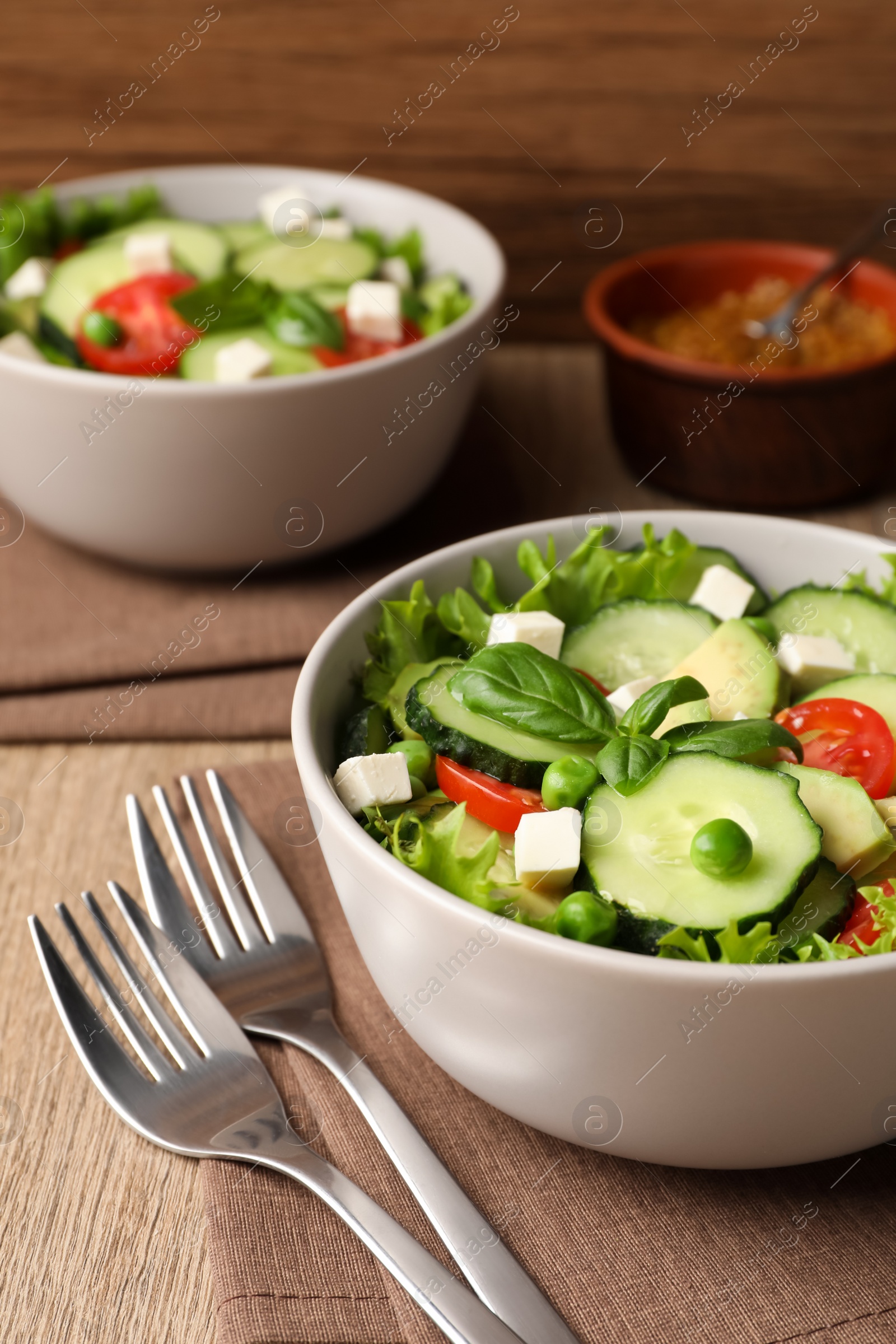 Photo of Tasty fresh salad with cucumber served on wooden table