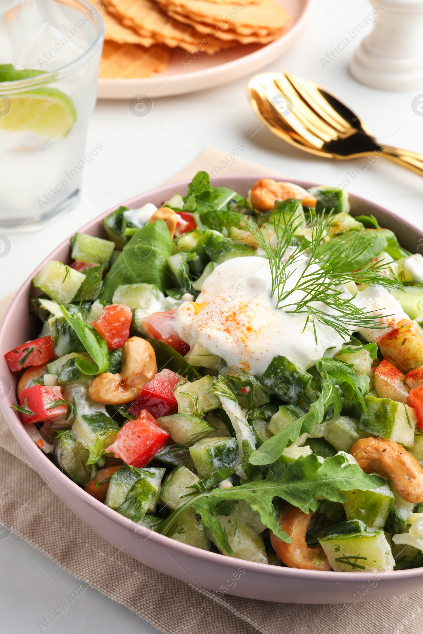 Photo of Bowl of delicious cucumber salad served on white table, closeup