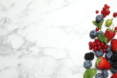 Mix of fresh berries on white marble table, flat lay. Space for text