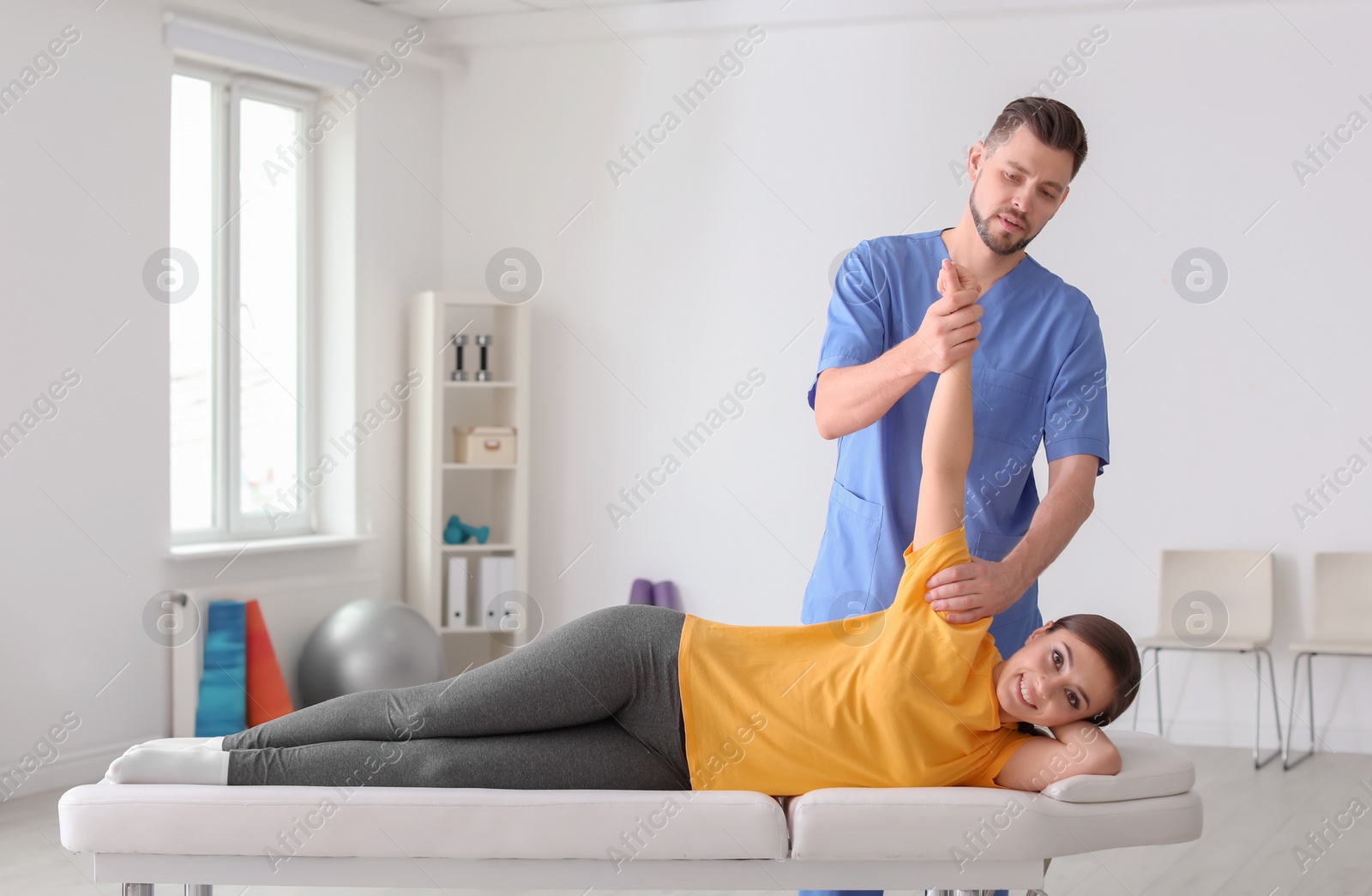 Photo of Physiotherapist working with female patient in clinic