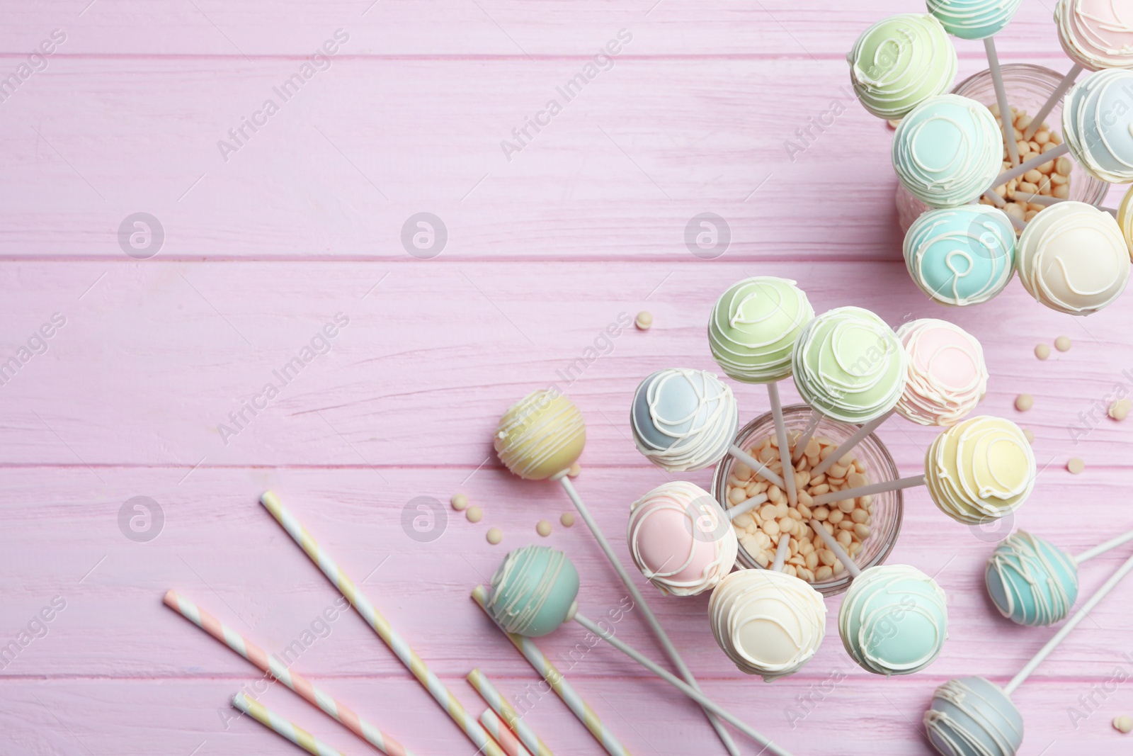 Photo of Sweet cake pops on pink wooden background, flat lay. Space for text