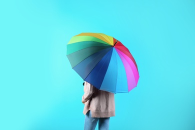 Woman with rainbow umbrella on color background