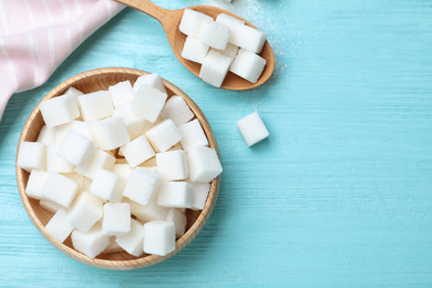 Refined sugar cubes on blue wooden table, flat lay. Space for text