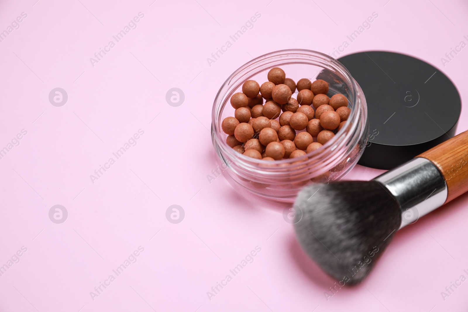 Photo of Face powder balls and brush on pink background, space for text