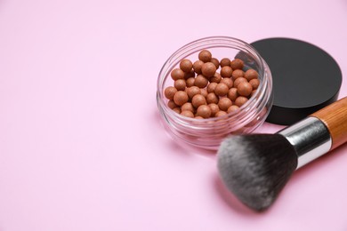 Photo of Face powder balls and brush on pink background, space for text
