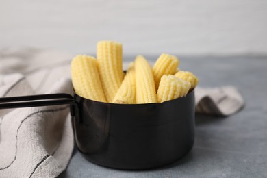 Tasty fresh yellow baby corns in dish on grey table, closeup