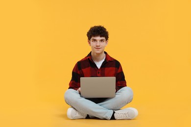 Photo of Portrait of student with laptop on orange background