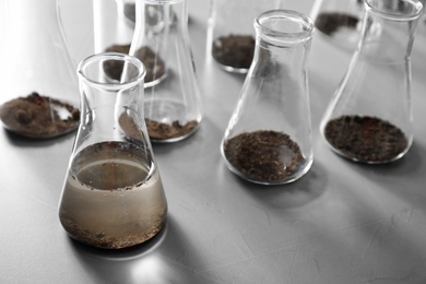 Photo of Glassware with soil samples and extract on grey table. Laboratory research
