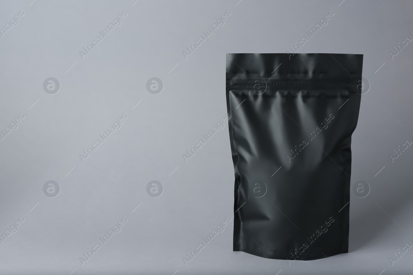 Photo of One blank foil package on grey background. Space for text