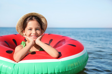 Cute little child with inflatable ring in sea on sunny day. Beach holiday