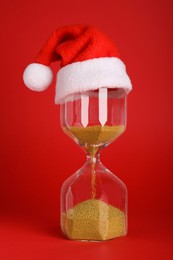 Hourglass and Santa hat on red background. Christmas countdown