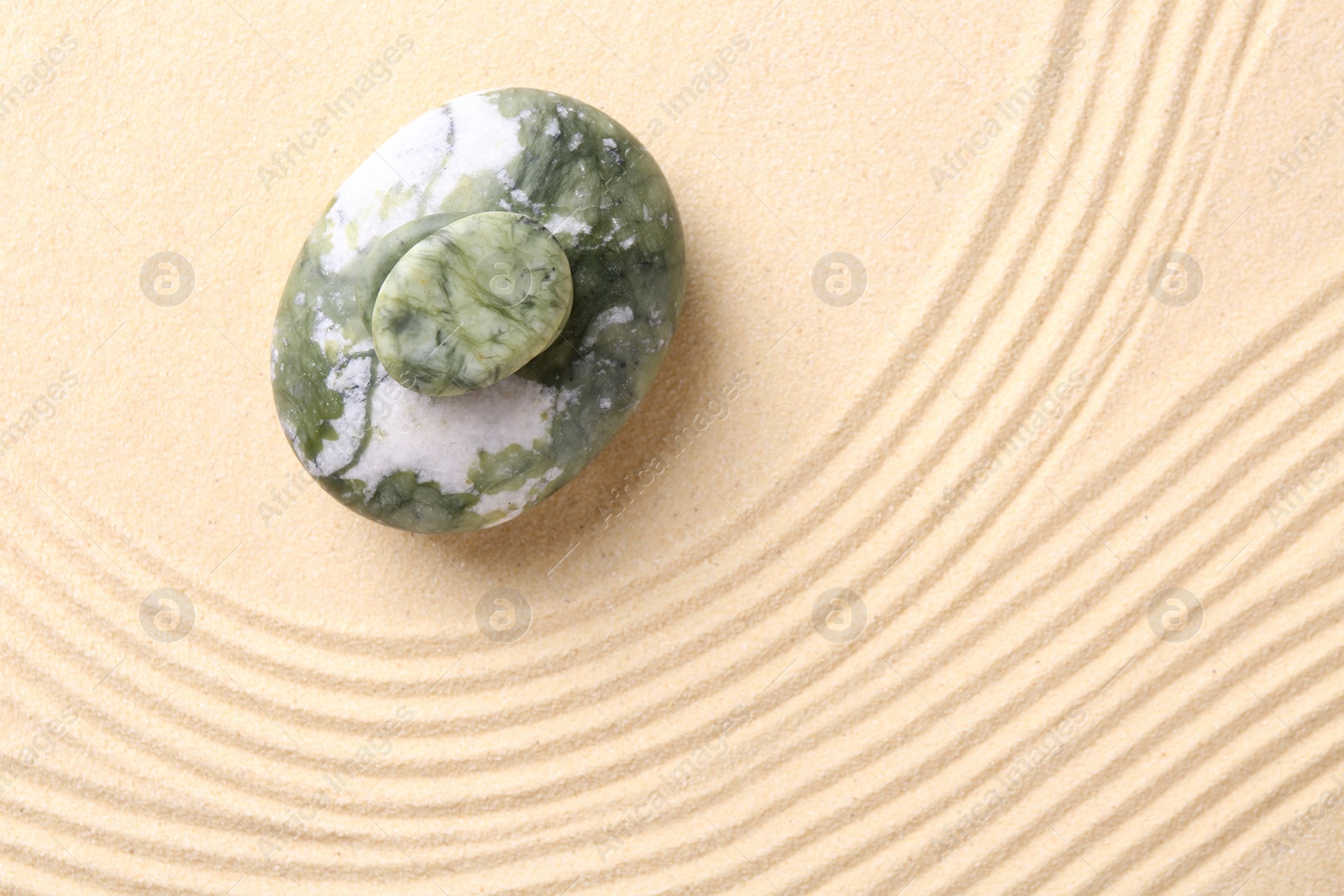 Photo of Zen concept. Stones and pattern on beige sand, top view. Space for text