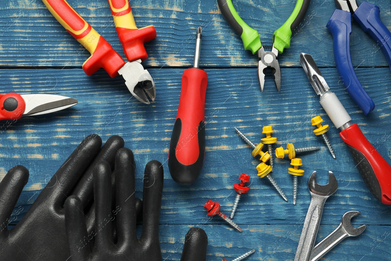 Photo of Different pliers, screwdriver and other tools for repair on blue wooden table, flat lay