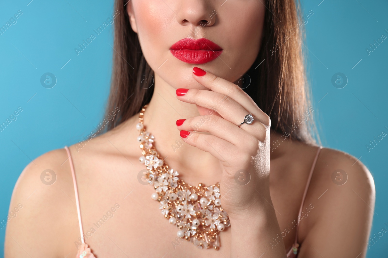 Photo of Beautiful woman with stylish jewelry on color background, closeup