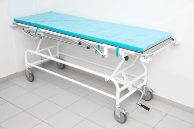 Medical trolley bed near wall in modern clinic