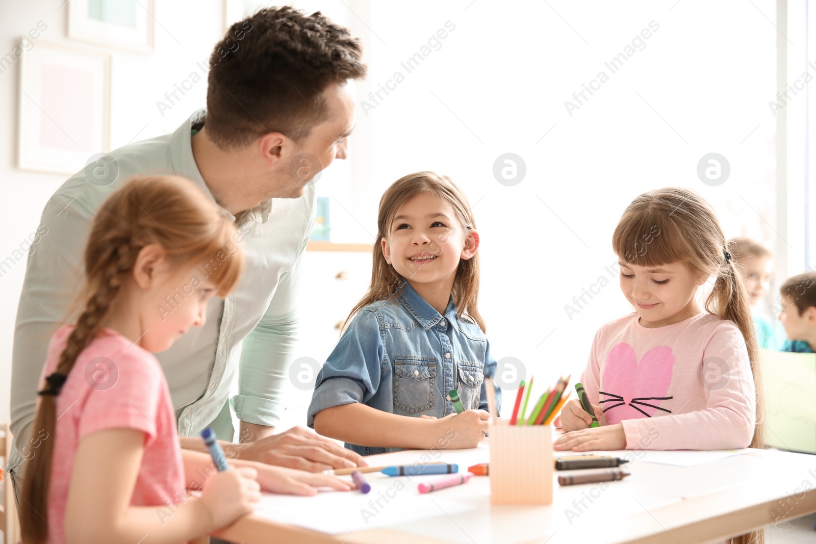 Photo of Cute little children with teacher in classroom at school