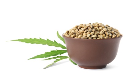 Photo of Bowl of hemp seeds with green leaf on white background