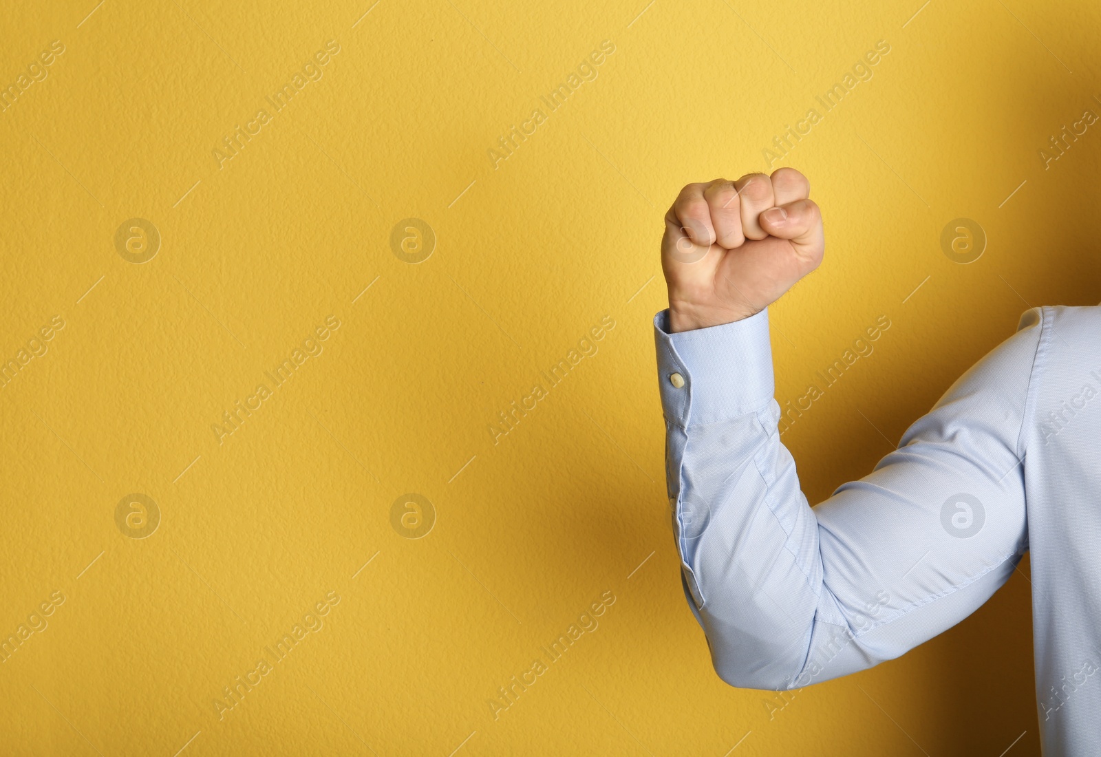 Photo of Young man showing clenched fist on color background. Space for text