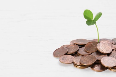 Photo of Coins with green sprout on white wooden table, closeup, space for text. Investment concept