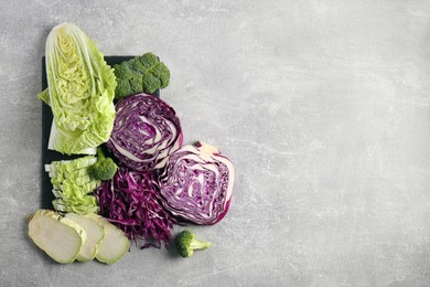Photo of Different types of cut cabbage on light grey table, flat lay. Space for text