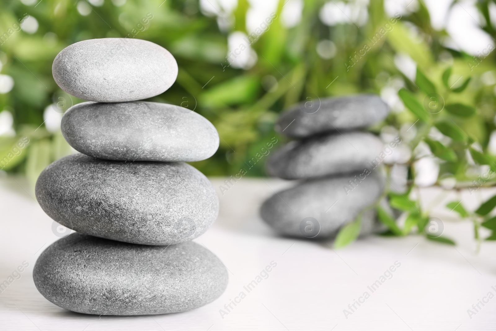 Photo of Spa stones and bamboo leaves on table against blurred background. Space for text