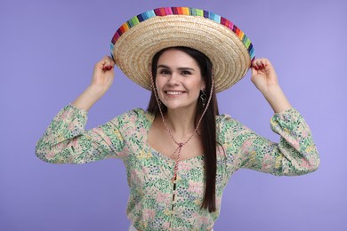 Young woman in Mexican sombrero hat on violet background