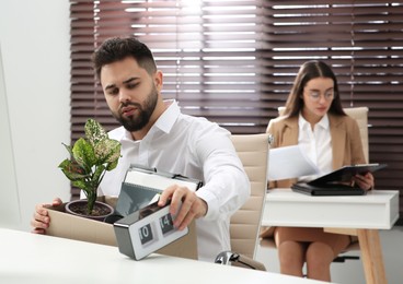 Photo of Dismissed man packing personal stuff into box in office