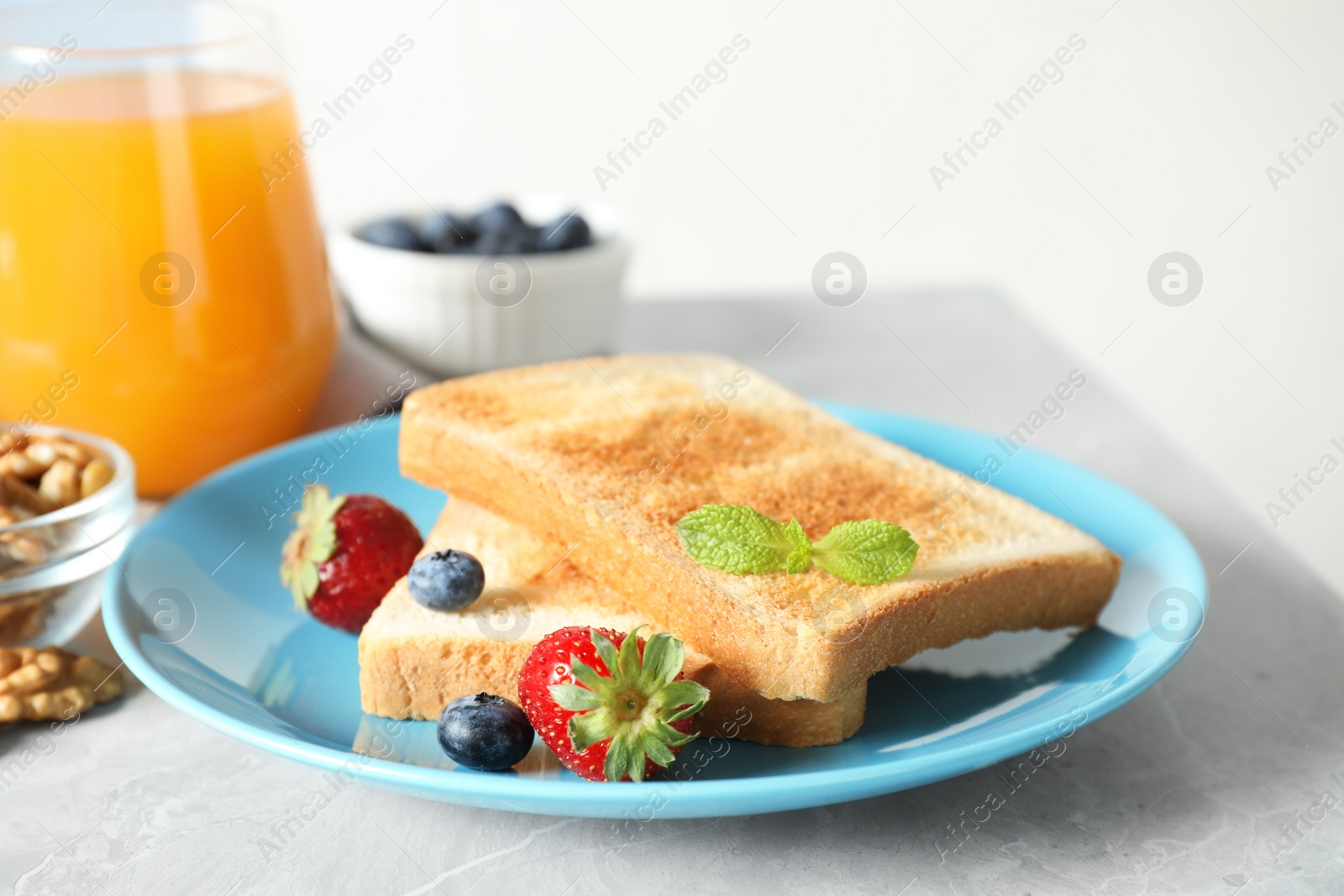 Photo of Delicious breakfast with toasted bread and berries on light grey marble table, closeup