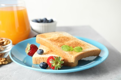 Delicious breakfast with toasted bread and berries on light grey marble table, closeup