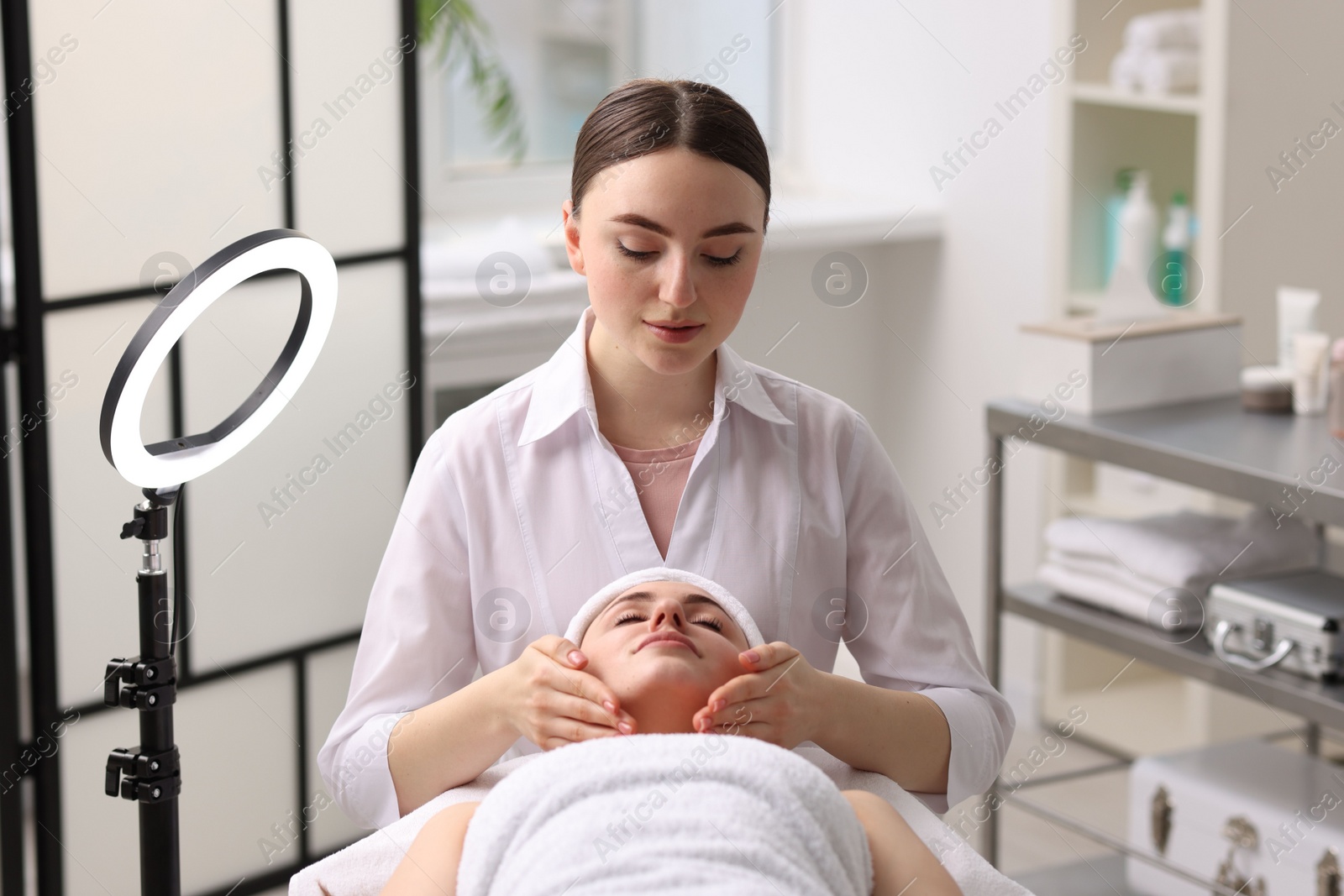 Photo of Cosmetologist making face massage to client in clinic