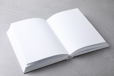 Photo of Open book with blank pages on light grey stone background. Mock up for design
